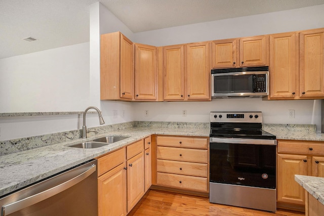 kitchen featuring light hardwood / wood-style flooring, light brown cabinetry, sink, light stone countertops, and stainless steel appliances