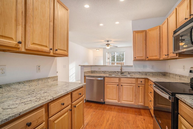 kitchen with appliances with stainless steel finishes, sink, light wood-type flooring, ceiling fan, and light stone counters