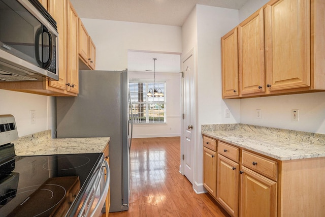 kitchen with a notable chandelier, appliances with stainless steel finishes, light wood-type flooring, decorative light fixtures, and light stone counters