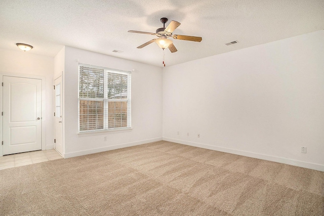 spare room with ceiling fan, light colored carpet, and a textured ceiling