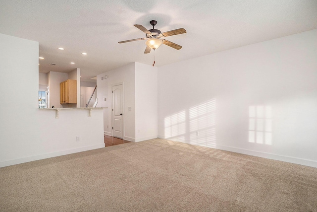 unfurnished living room featuring ceiling fan and dark carpet