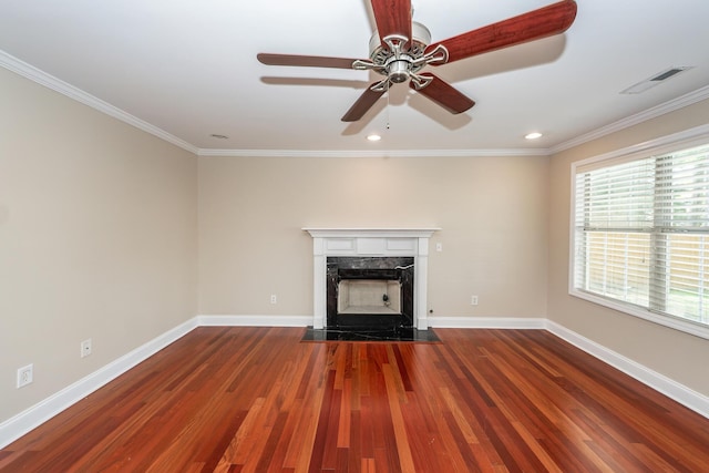unfurnished living room featuring ceiling fan, wood finished floors, a high end fireplace, visible vents, and ornamental molding