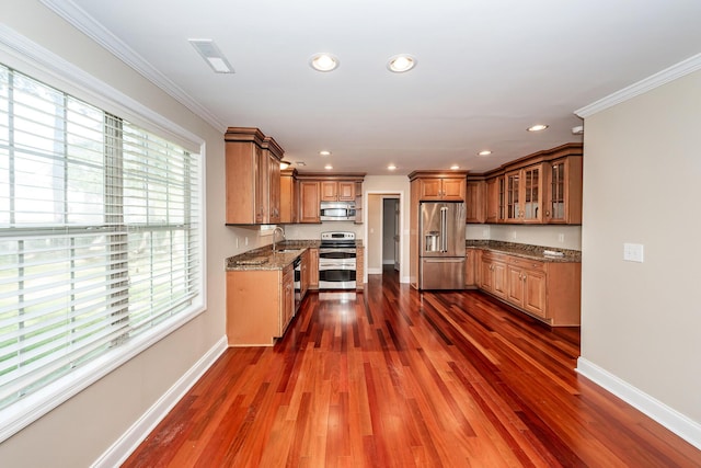 kitchen with baseboards, a sink, brown cabinets, and stainless steel appliances