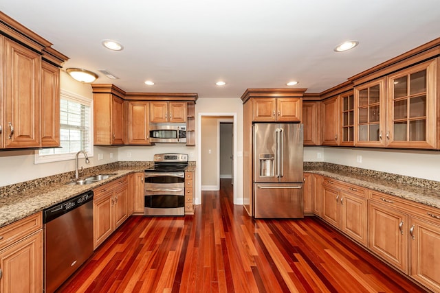 kitchen with brown cabinetry, visible vents, light stone countertops, a sink, and stainless steel appliances