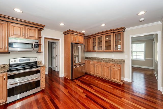 kitchen featuring appliances with stainless steel finishes, light stone countertops, baseboards, ornamental molding, and dark wood-type flooring