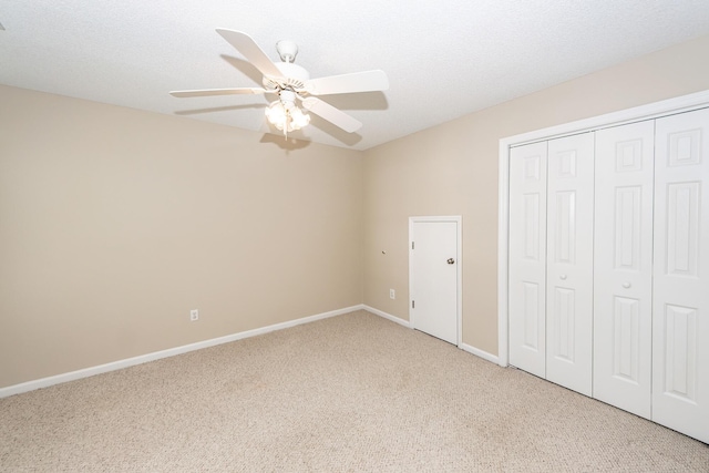 unfurnished bedroom with light colored carpet, baseboards, ceiling fan, and a closet