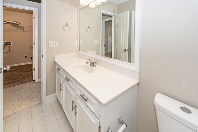 bathroom with tile patterned flooring, vanity, toilet, baseboards, and a spacious closet