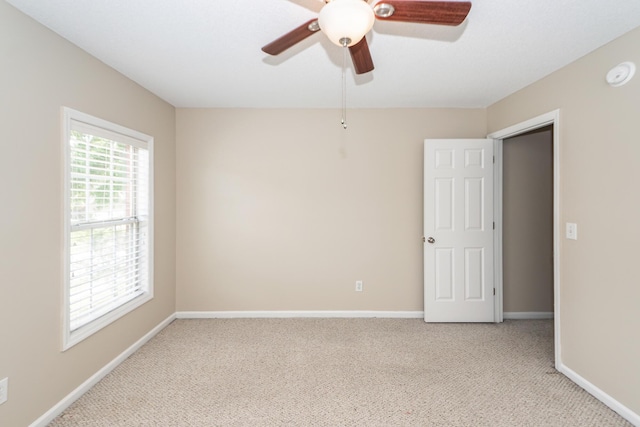 unfurnished room featuring a ceiling fan, baseboards, and light colored carpet