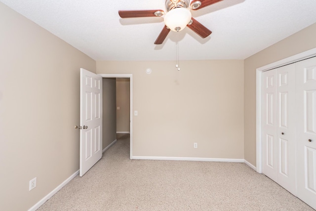 unfurnished bedroom featuring baseboards, light colored carpet, ceiling fan, and a closet