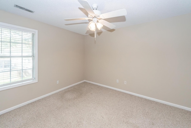 carpeted spare room featuring baseboards, a wealth of natural light, ceiling fan, and visible vents