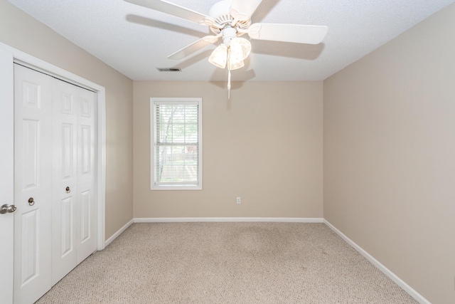 unfurnished bedroom featuring visible vents, baseboards, a closet, and light carpet