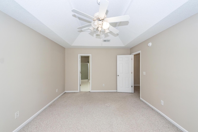 unfurnished bedroom with carpet floors, a ceiling fan, baseboards, a tray ceiling, and visible vents