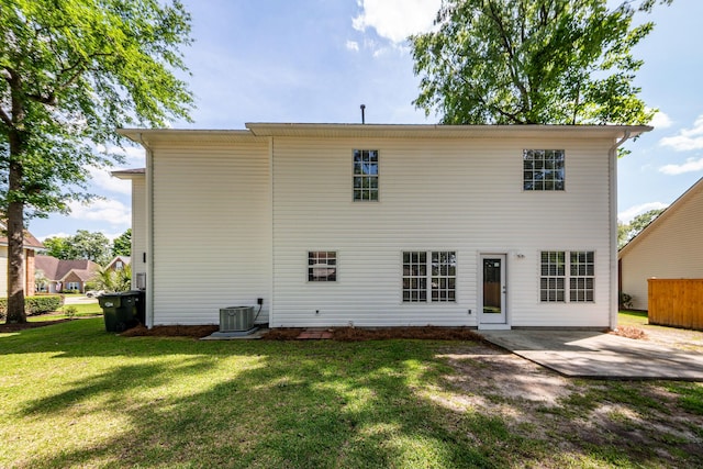 rear view of property featuring a lawn, central AC, and a patio area