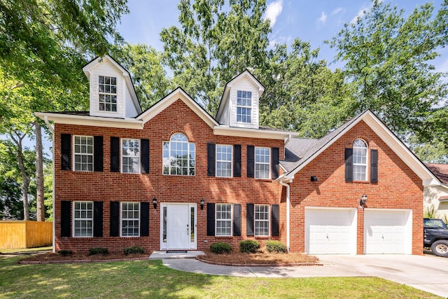 colonial home with a garage, brick siding, fence, a front lawn, and concrete driveway