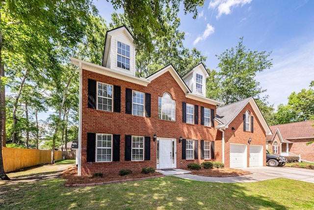 colonial inspired home featuring fence, a front lawn, brick siding, a garage, and driveway