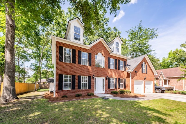 colonial house with a garage, fence, a front yard, brick siding, and concrete driveway