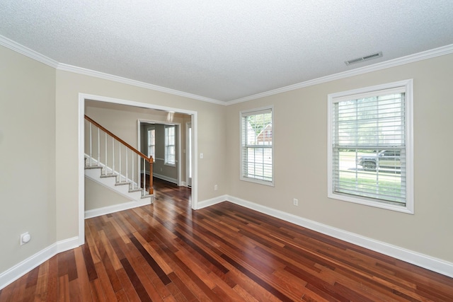 empty room with visible vents, a textured ceiling, dark wood-style flooring, and ornamental molding