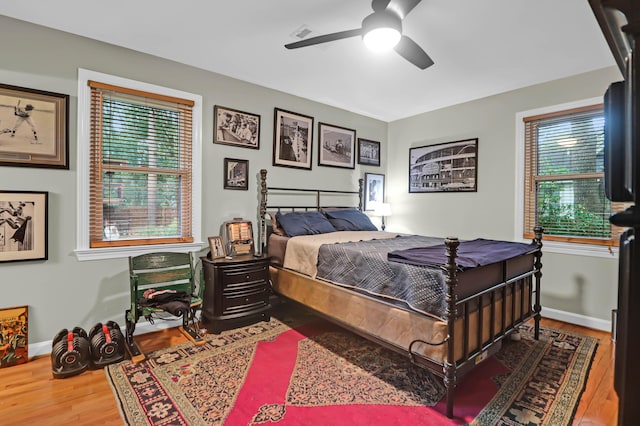 bedroom with ceiling fan, multiple windows, and hardwood / wood-style floors