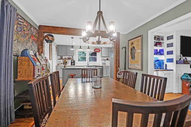 dining area with an inviting chandelier, ornamental molding, and sink