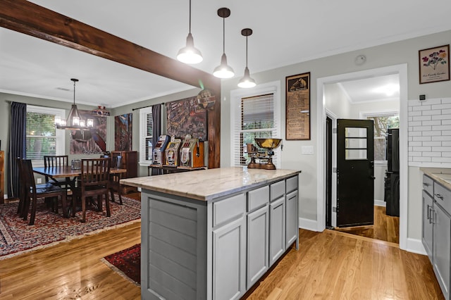 kitchen with a center island, light stone counters, hanging light fixtures, and gray cabinets