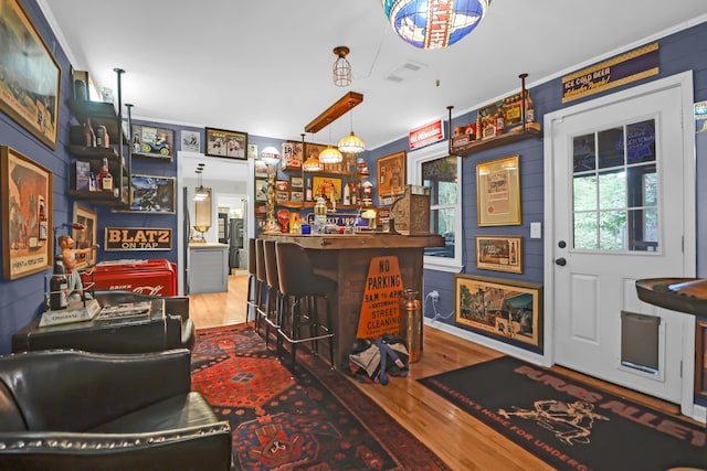 bar featuring ornamental molding and wood-type flooring