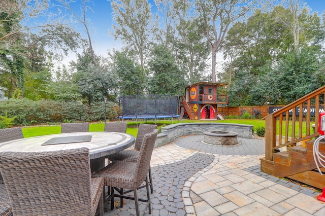 view of patio featuring an outdoor fire pit, a trampoline, and a playground