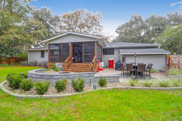 rear view of property with a sunroom, a yard, and a patio