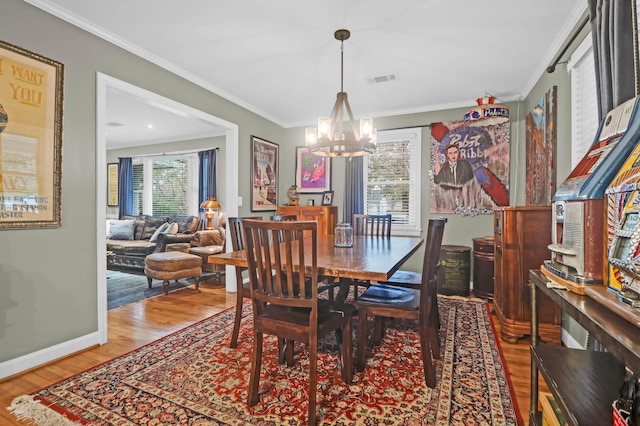 dining room featuring hardwood / wood-style flooring, crown molding, and a notable chandelier