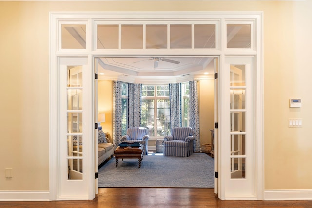 living room featuring ornamental molding, wood-type flooring, ceiling fan, and a raised ceiling