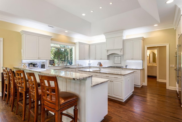 kitchen featuring light stone countertops, white cabinets, kitchen peninsula, and decorative backsplash