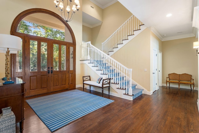 foyer entrance with an inviting chandelier, crown molding, a towering ceiling, and dark hardwood / wood-style floors