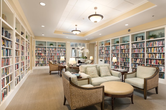 sitting room featuring a tray ceiling, built in features, and light colored carpet