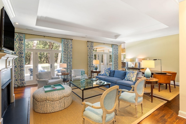 living room with a raised ceiling, crown molding, dark hardwood / wood-style flooring, and french doors