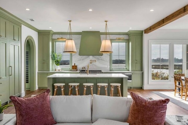 kitchen with decorative light fixtures, decorative backsplash, green cabinetry, and wall chimney exhaust hood