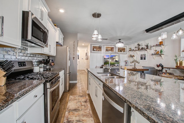 kitchen featuring light wood-style flooring, a sink, backsplash, appliances with stainless steel finishes, and white cabinets