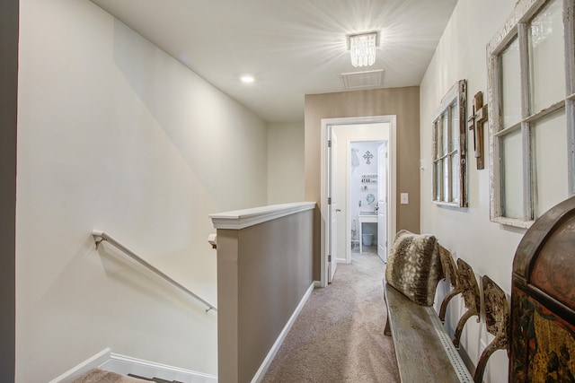 corridor featuring baseboards, an upstairs landing, carpet, and visible vents