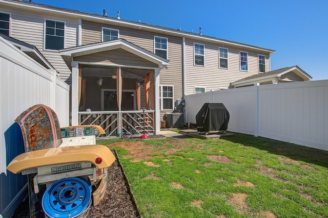 rear view of house with a yard, a fenced backyard, and a sunroom