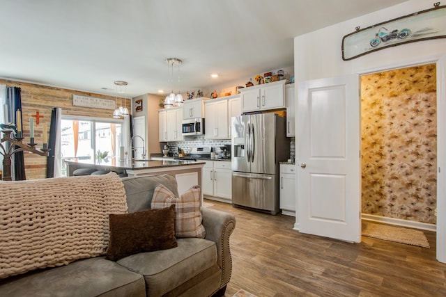 kitchen featuring dark wood-style flooring, stainless steel appliances, white cabinets, dark countertops, and open floor plan