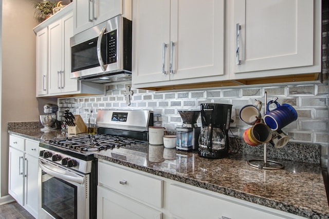 kitchen with decorative backsplash, dark stone counters, white cabinets, and appliances with stainless steel finishes