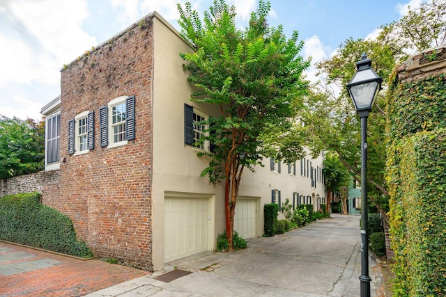 2 Bedons Aly, Charleston, SC 29401 - view of side of home featuring an attached garage, brick siding, and driveway