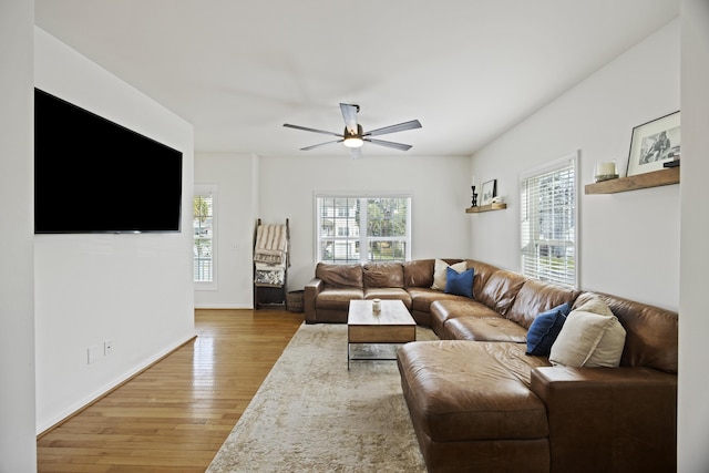 living area featuring light wood-style flooring, a ceiling fan, and baseboards