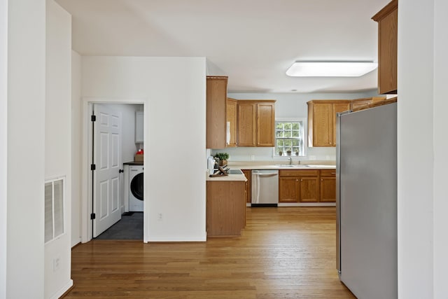 kitchen featuring visible vents, light wood-type flooring, light countertops, brown cabinets, and stainless steel appliances