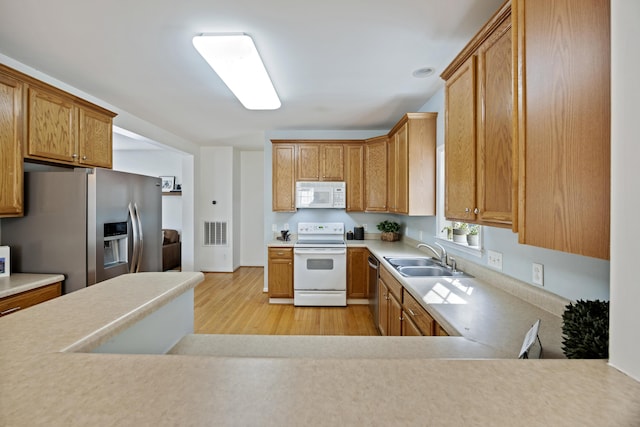 kitchen featuring visible vents, light wood-style flooring, a sink, appliances with stainless steel finishes, and light countertops