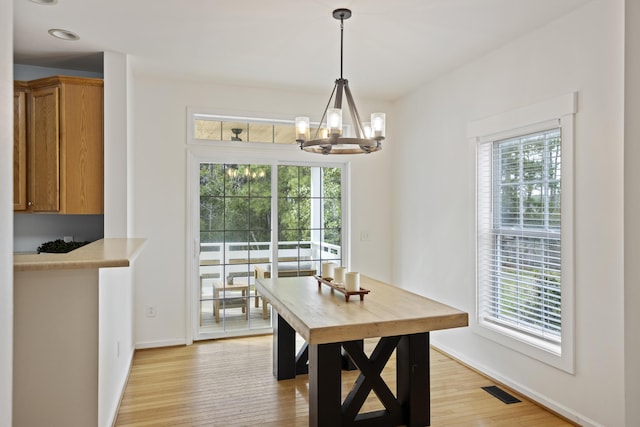 dining area featuring light wood finished floors, a wealth of natural light, and a chandelier