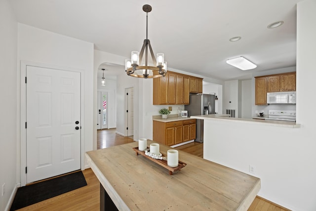 dining room with baseboards, light wood-type flooring, and an inviting chandelier