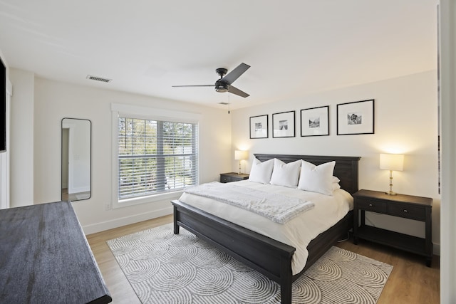 bedroom with visible vents, light wood-style flooring, baseboards, and a ceiling fan