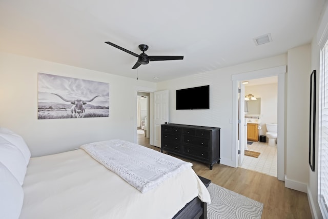 bedroom with ceiling fan, visible vents, ensuite bath, and light wood finished floors