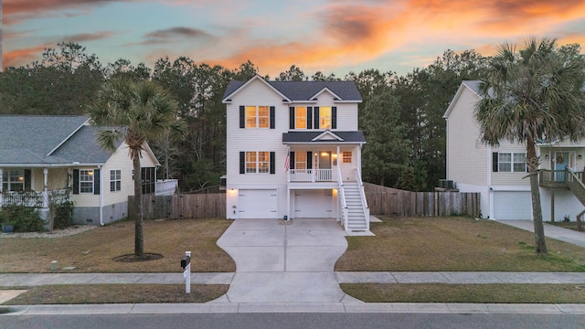 view of front of property featuring stairway, driveway, covered porch, a front lawn, and a garage