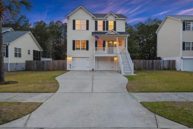 coastal inspired home with driveway, a front lawn, a porch, a garage, and stairs