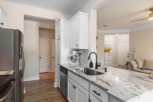 kitchen with appliances with stainless steel finishes, ornamental molding, white cabinetry, a sink, and light stone countertops